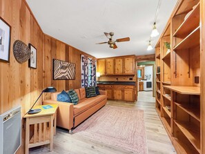 A cozy room with a wooden floor, a sofa, a small table with a lamp, and a ceiling fan. - Modern 3BR Retreat with Sauna & Hot Tub Sleeps 8 (Sequim)