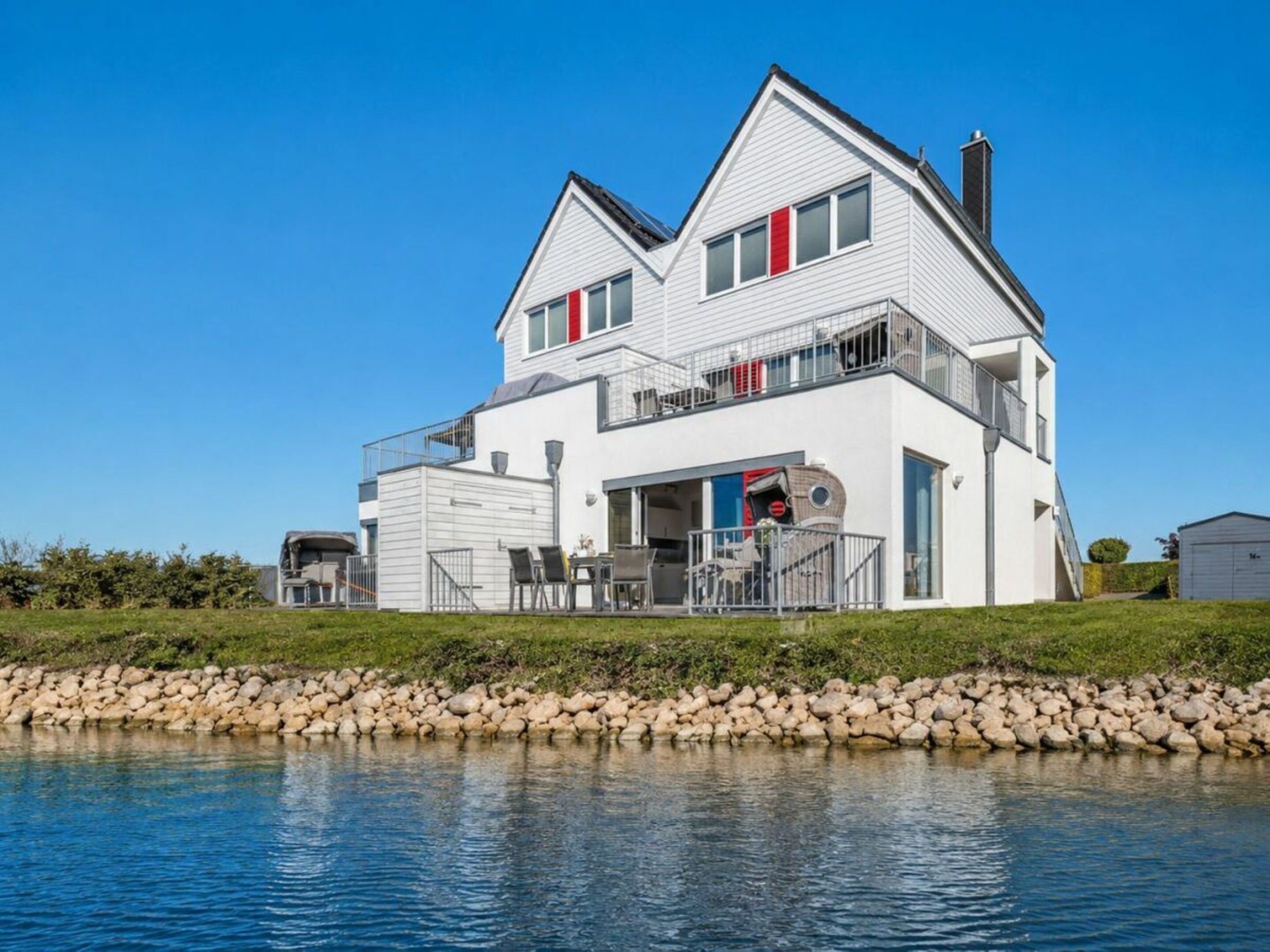 A two-story house with a balcony, a garage, and a pond in front.