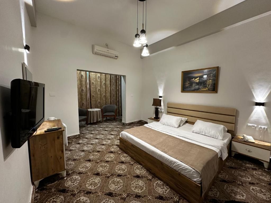 Een hotelkamer met een groot bed, een televisie, een bureau en een stoel.