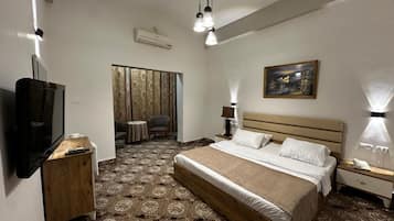 Een hotelkamer met een groot bed, een televisie, een bureau en een stoel.