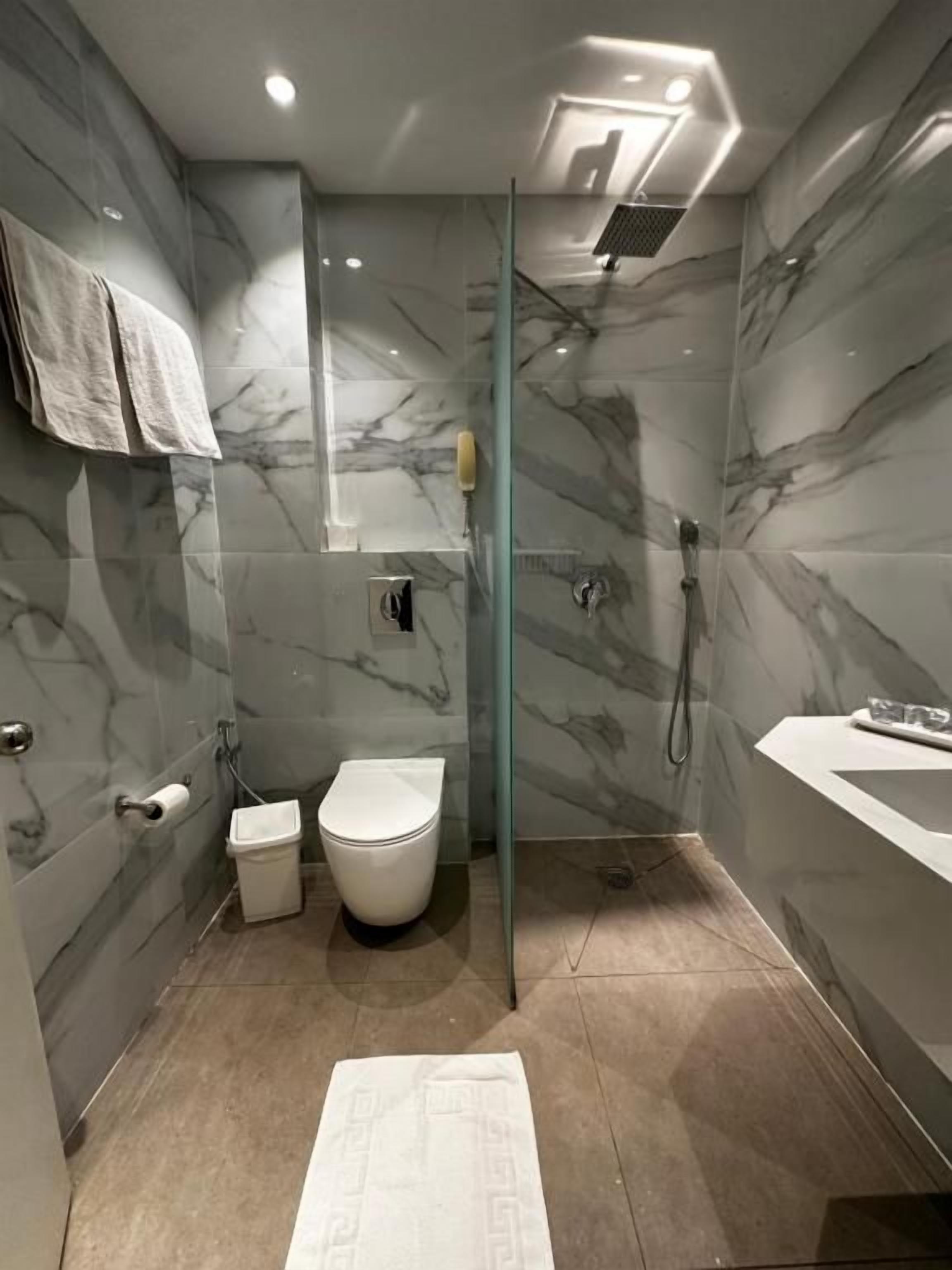 Un baño moderno con cabina de ducha de vidrio, inodoro y lavamanos.