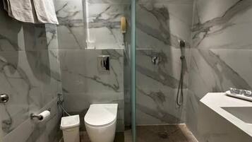 Un baño moderno con cabina de ducha de vidrio, inodoro y lavamanos.