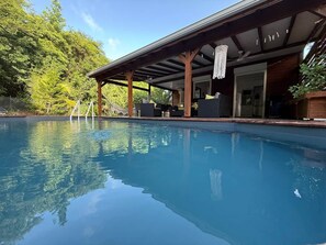 Une piscine dotée d’un espace couvert et de mobilier d’extérieur.