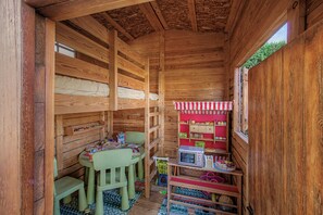 A compact wooden room with bunk beds, a small table, chairs, a microwave, and a toy kitchen set. - Holiday Home 'Casa Arrels' with Montseny Views (Sant Julià d'Alfou)