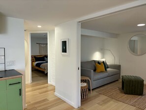 Et moderne opholdsrum med en sofa, et grønt skab og en seng i baggrunden.
