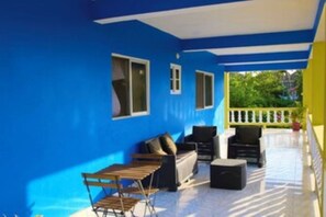 Ein überdachter Außenbereich mit einer blauen Wand, einem Tisch und Stühlen.