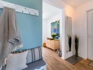 A room with a blue wall, a wooden bench with cushions, a white cabinet, and a painting. - Holiday Apartment With 2 Bedrooms (Kappeln)