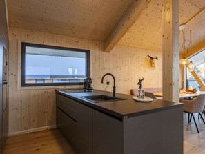Eine moderne Küche mit Holzwänden, einem großen Fenster und einer zentralen Kochinsel mit Spüle.