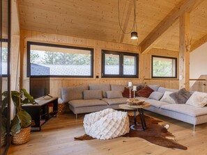 Ein gemütliches Wohnzimmer mit einer Eckcouch, einem Couchtisch und einem großen Fenster, das für natürliches Licht sorgt.