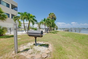 A mailbox in a grassy area with a body of water and a dock in the background. - Bay Views & Heated Pool | Coastal 2BR Retreat (Bradenton Beach)