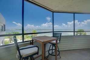 Een balkon met een tafel en stoelen, uitkijkend op een wateroppervlak met een heldere lucht.