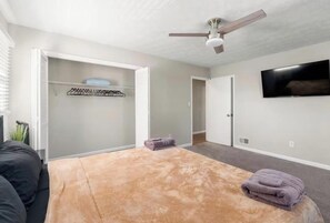 A bedroom with a bed, a ceiling fan, a TV on the wall, and a closet with hanging clothes. - Event Friendly Private 6 bedroom Pool
house in Atlanta (Atlanta)