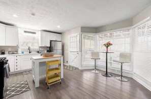 A modern kitchen with white cabinetry, a central island, and a dining area with two chairs and a table. - Event Friendly Private 6 bedroom Pool
house in Atlanta (Atlanta)