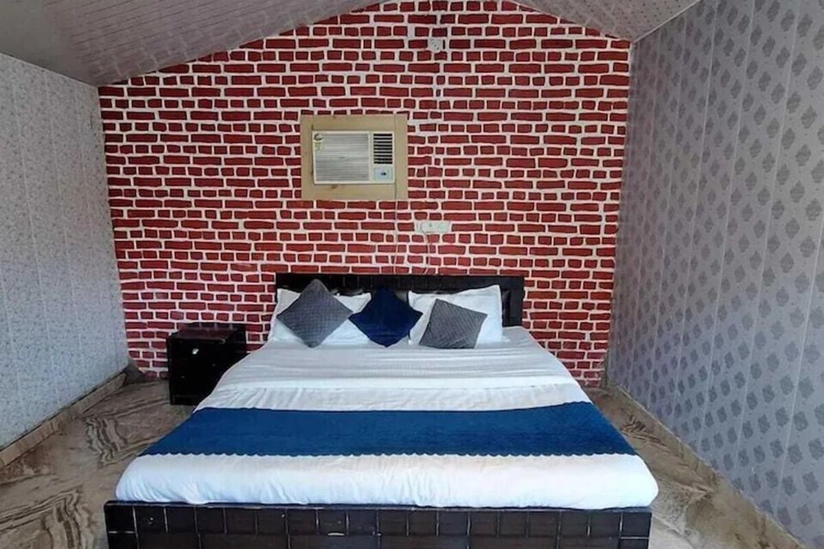Uma cama de solteiro com cabeceira, um ar condicionado fixado na parede e um papel de parede estampado na parede ao lado.