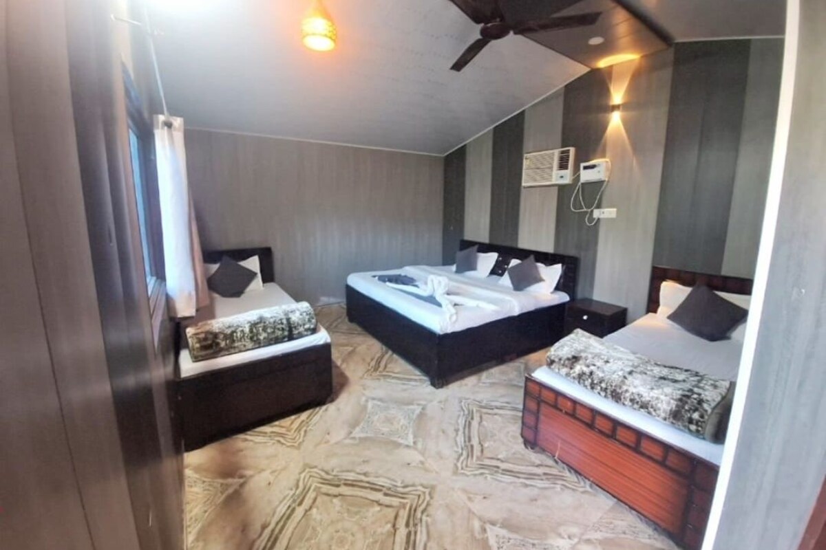 Quarto de hotel com duas camas, um ventilador de teto e um aparelho de ar condicionado.