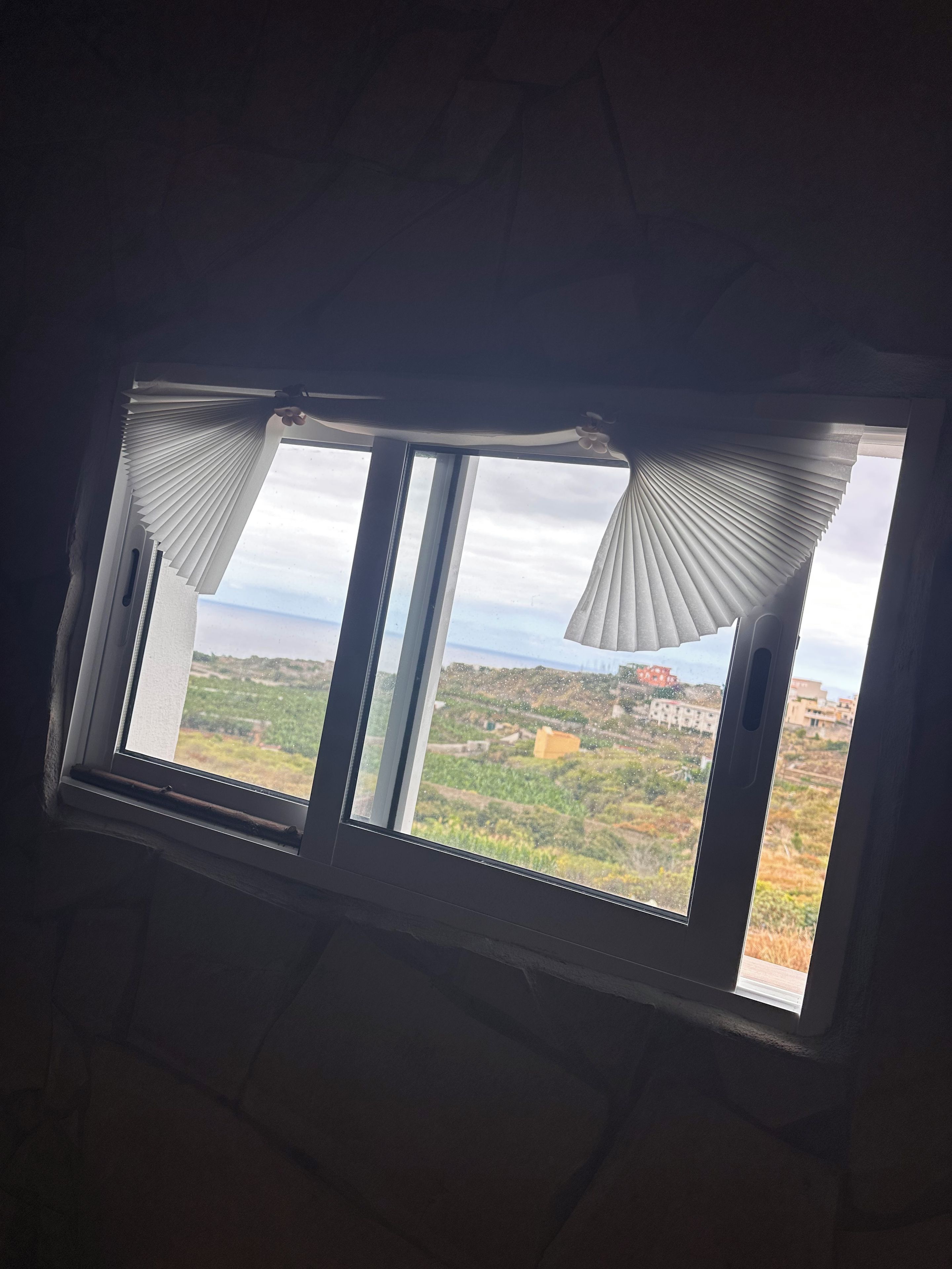 Un tragaluz con vistas a un paisaje, que incluye edificios y vegetación.