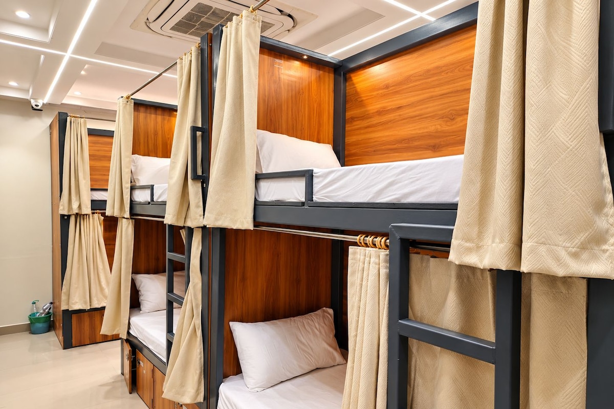 A hotel room with bunk beds, wooden headboards, and beige curtains.