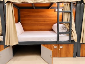 A bunk bed with a wooden headboard, beige curtains, and a pull-out drawer cabinet. - S.G.P - Premium Dormitory  (Mathura)