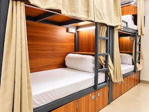 A bunk bed with wooden headboard and side panels, a bedside table, and a small cabinet with drawers. - S.G.P - Premium Dormitory  (Mathura)