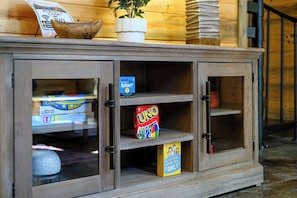 A wooden cabinet with glass doors, containing board games and a potted plant. - 3 Private King Suites | Hot Tub, Playset, PingPong (Broken Bow)