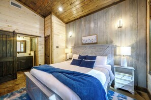 A bedroom with a bed, bedside tables, a nightstand, a mirror, and a door. - 3 Private King Suites | Hot Tub, Playset, PingPong (Broken Bow)