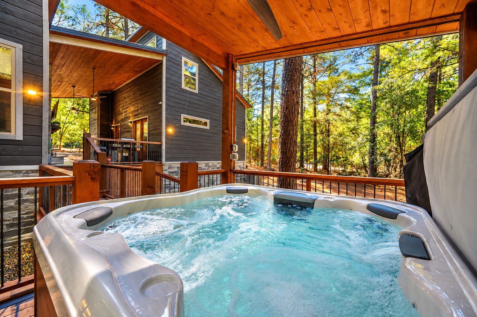 A hot tub on a wooden deck with a view of a forest.