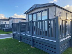 En campingvogn med terrasse og indhegnet område.