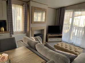 En moderne stue med en sofa, et fjernsyn på et træstel og en pejs.