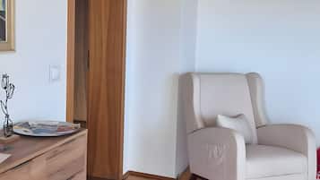 A room with a wooden herringbone floor, a white sofa, and a wooden cabinet.