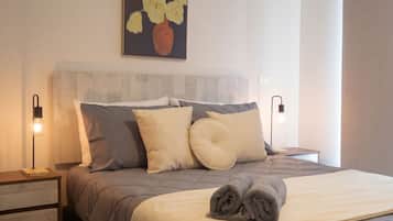 Une chambre à coucher moderne, comprenant un lit, des tables de chevet, une tête de lit et une œuvre d’art accrochée au mur.