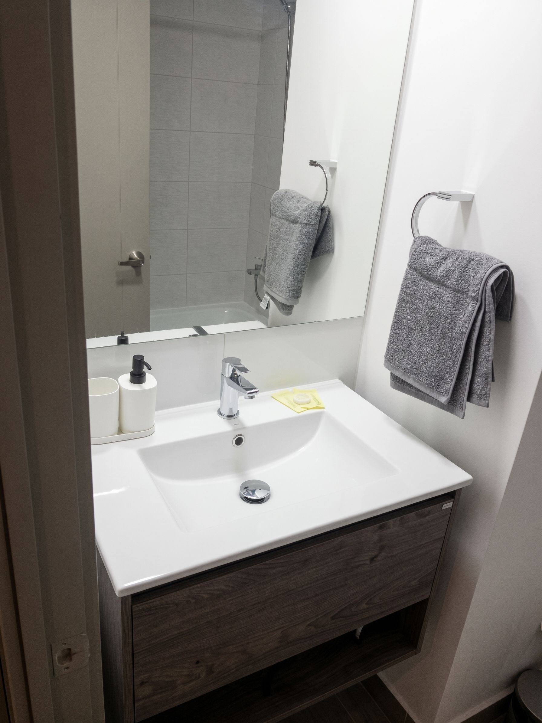 Une salle de bain moderne avec un lavabo blanc, un miroir et un porte-serviettes.