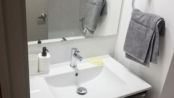 Une salle de bain moderne avec un lavabo blanc, un miroir et un porte-serviettes.
