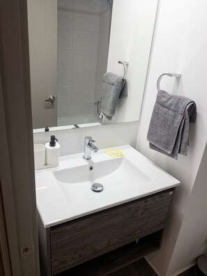 A modern bathroom with a white sink, a mirror, and a towel rack. - Edificio Arturo Prat by Domus Travels (Santiago)
