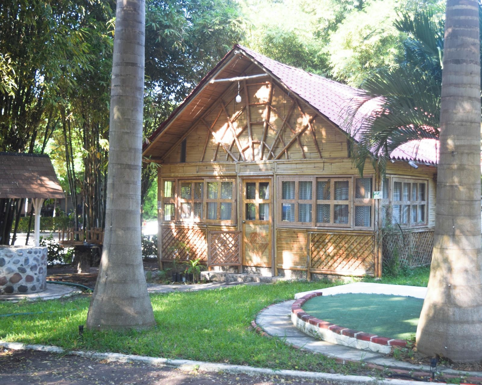 Uma casa de madeira com telhado inclinado, cercada por um gramado bem cuidado e árvores.