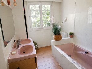 A bathroom with a double sink, a bathtub, a window with a view of greenery, and a potted plant. - 6 bedrooms • Perfect for Christmas near Nantes (Vertou)