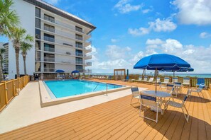 A pool area with a wooden deck, lounge chairs, and umbrellas. - 🏖️ Windward 307 | Beach Front 🌴Private Balcony | Pools 🏊‍♀️ (Panama City Beach)