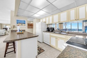 A modern kitchen with granite countertops, white cabinetry, and a built-in dishwasher. - 🏖️ Windward 307 | Beach Front 🌴Private Balcony | Pools 🏊‍♀️ (Panama City Beach)