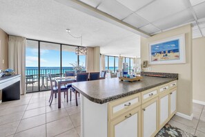 Een ruime keuken met een groot schiereiland, een eethoek met uitzicht op de oceaan, en een balkon met uitzicht op zee.