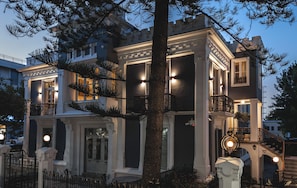 Un edificio de varios pisos con una entrada imponente, múltiples balcones y una fachada bien iluminada.