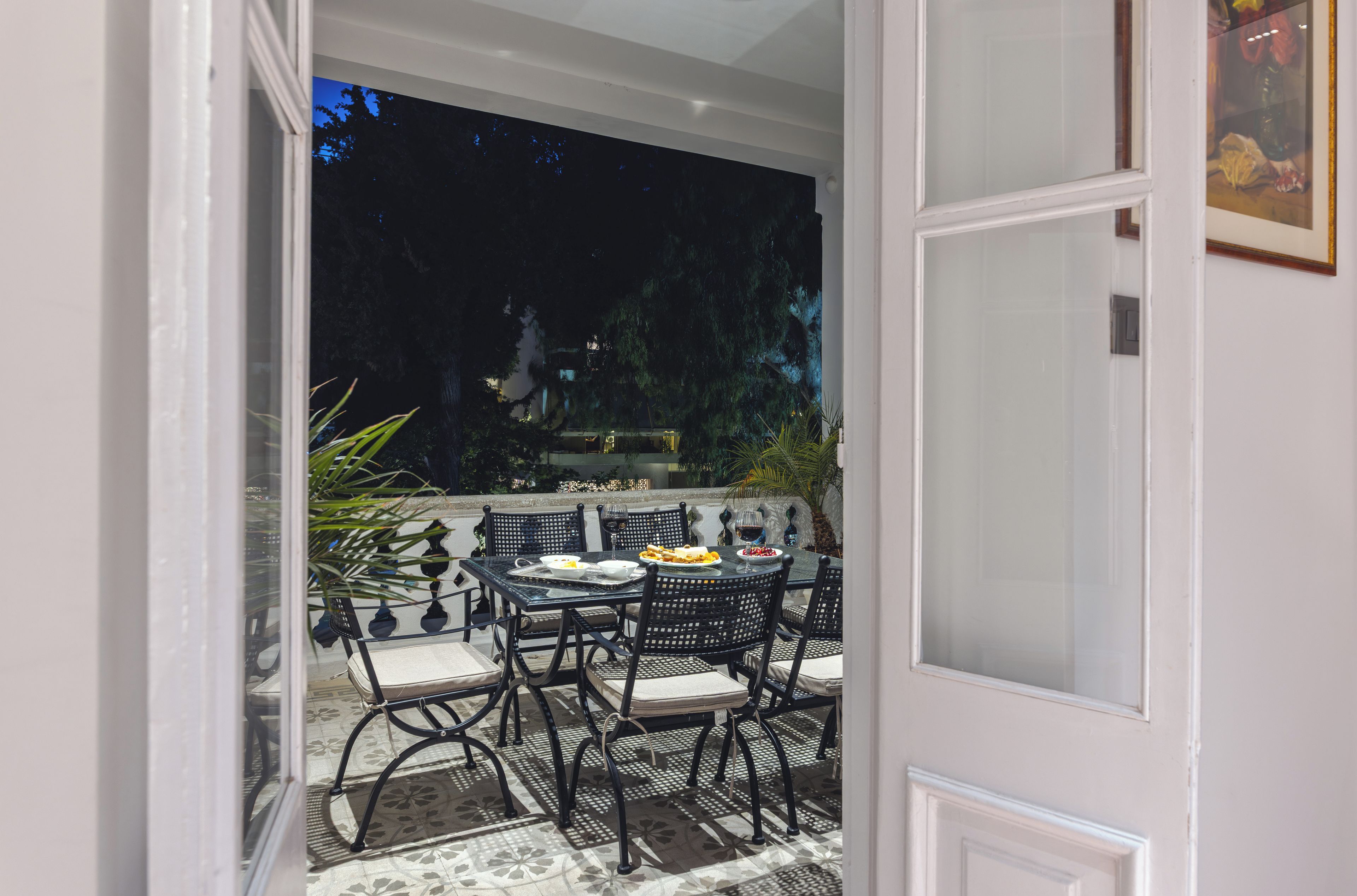 Un espacio exterior para comer con una mesa, sillas, un muro decorativo y vistas a árboles.