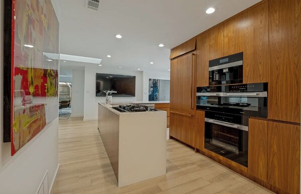Une cuisine moderne avec des meubles en bois, un îlot central et des appareils électroménagers intégrés.