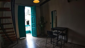A room with a dining table and chairs, a staircase, and a door leading outside. - Hotel La Casa de Laurita (Salento)