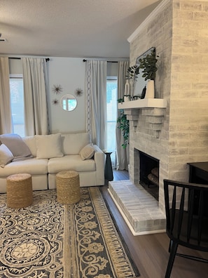 A living room with a sofa, a fireplace, a rug, and a dining area. - Fantastic 2-bedroom townhome in North Charleston (North Charleston)