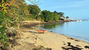 A beach with a boat, pebbles, and a calm sea.