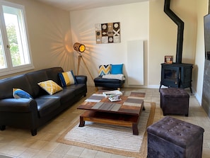 Una sala de estar con sofá, mesa de centro, reposapiés y chimenea.