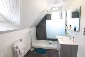 Un baño moderno con ducha, lavamanos y un perchero para toallas.