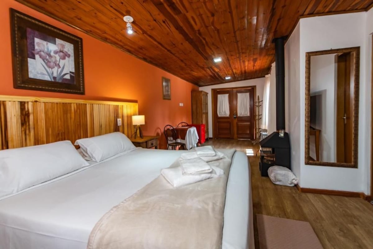 Quarto de hotel com cama grande, teto de madeira e espelho na parede.