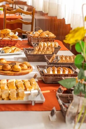 Mesa de buffet com pães e doces variados.