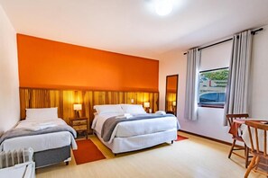 Quarto de hotel com uma cama grande, duas mesas de cabeceira, uma cadeira e uma janela com cortinas.