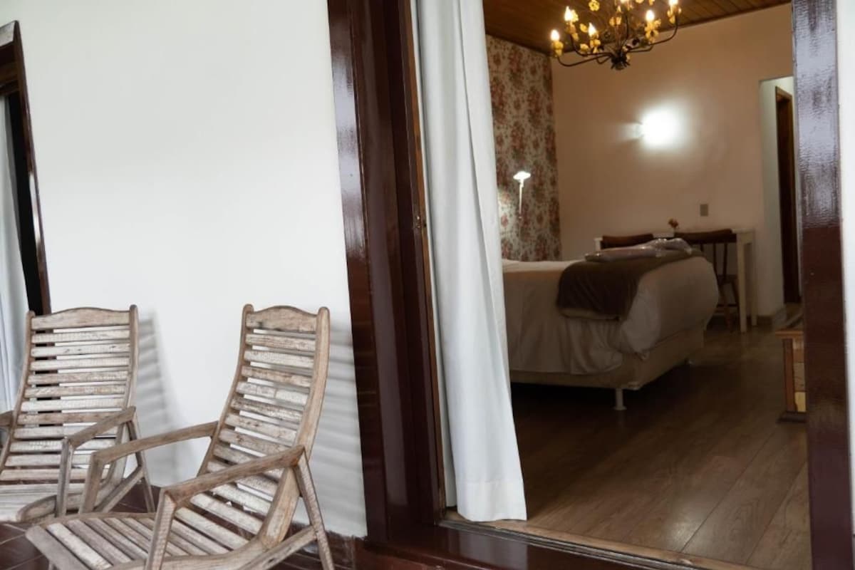 Quarto com cama, mesa de cabeceira e uma cadeira.